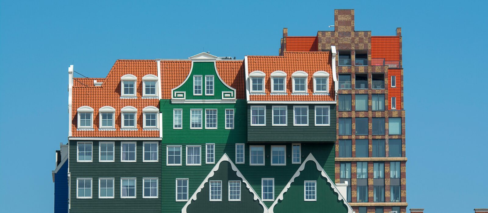 Vibrant facade of Inntel Hotels in Zaandam, featuring colorful, traditional Dutch architecture under a clear blue sky.
